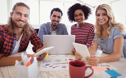 Four young adults collaborating with laptop and tablets